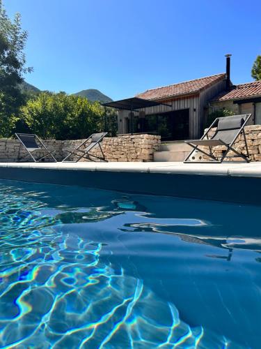 une piscine d'eau avec des chaises et une maison dans l'établissement La station en Drôme Provencale, à Vesc