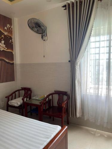 a room with a bed and two chairs and a window at KHÁCH SẠN MlLAN in Dĩ An