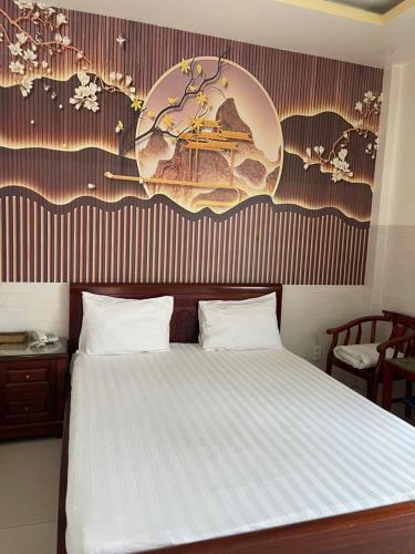 a bedroom with a bed with a painting on the wall at KHÁCH SẠN MlLAN in Dĩ An