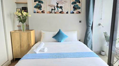 - une chambre avec un lit blanc aux accents bleus dans l'établissement Vinhomes Greenbay Studio Luxury Apt #Jerry's House, à Hanoï