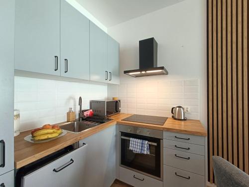 Una cocina con gabinetes blancos y un plato de fruta en la encimera. en Apartament Baltic Sauna Break e-apart, en Władysławowo