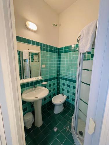 a green tiled bathroom with a sink and a toilet at Hotel Reale in Rimini