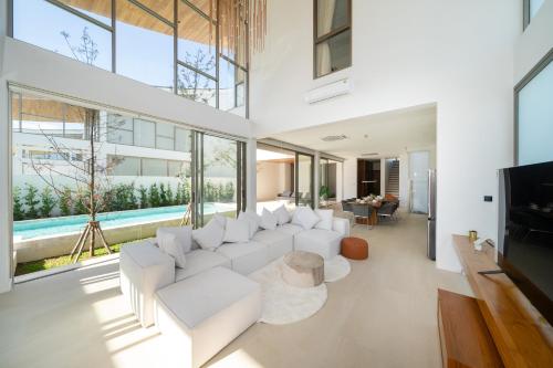 a living room with a white couch and a tv at 5BR Pool Villa with 20m Private Pool near Laguna Phuket - Trinity Villa by Warm Plus in Thalang