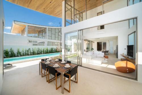 a living room with a table and a pool at 5BR Pool Villa with 20m Private Pool near Laguna Phuket - Trinity Villa by Warm Plus in Thalang