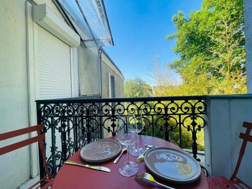 une table rouge avec des assiettes et des verres à vin sur un balcon dans l'établissement Casa Madeleine, à Angers