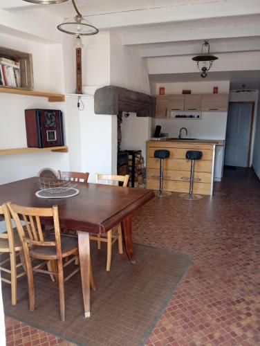 a kitchen and dining room with a wooden table and chairs at Maison du bourg in Mayres