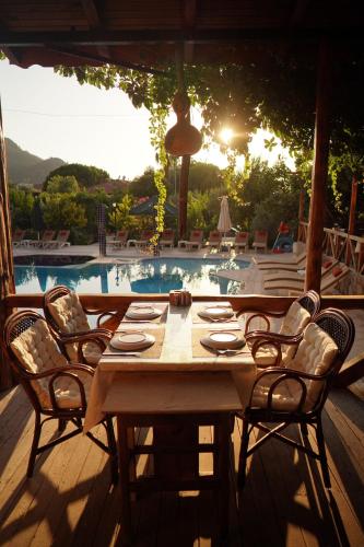 a wooden table and chairs with a pool in the background at Suzanne Hotel & Restaurant in Fethiye