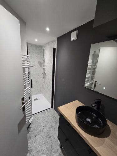 La salle de bains est pourvue d'un lavabo noir et d'une douche. dans l'établissement Le Lagon Saint Lary 8 pers classé 4 diamants 3 étoiles, à Saint-Lary-Soulan