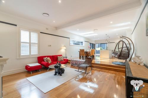 sala de estar con sofá rojo y silla roja en KozyGuru | Rose Bay | 3BR Steps to Beach + Parking, en Sídney