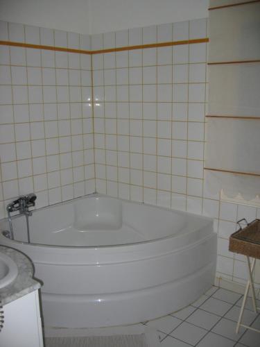 La salle de bains carrelée est pourvue d'une baignoire blanche et d'un lavabo. dans l'établissement Logis de la Paqueraie, à Saint-Branchs