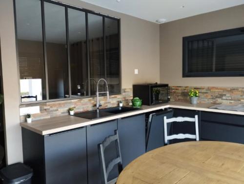 une cuisine avec un évier et une table avec des chaises dans l'établissement Villa Murène - Détente en bord de mer, entre Sérignan et Valras-Plage, à Sérignan