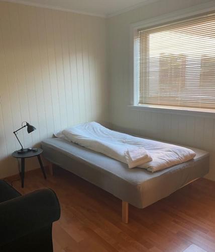 a bed in a room with a lamp and a window at Seljesanden Apartment in Selje
