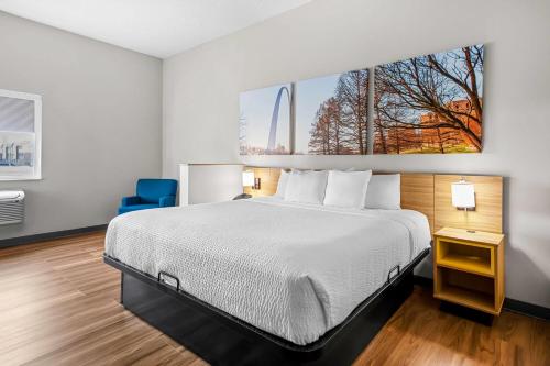 a hotel room with a bed and a blue chair at Days Inn by Wyndham Collinsville St Louis in Collinsville