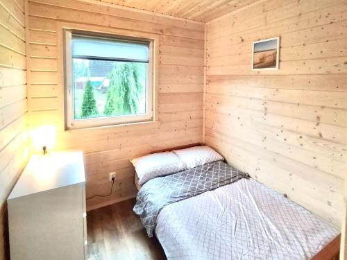 a small bedroom with a bed and a window at Domki Letniskowe SOHO in Bobolin