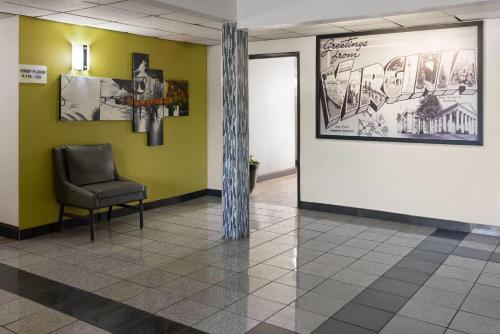 a waiting room with a chair and a poster on the wall at Super 8 by Wyndham South Boston VA in South Boston