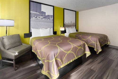 a hotel room with two beds and a chair at Super 8 by Wyndham South Boston VA in South Boston