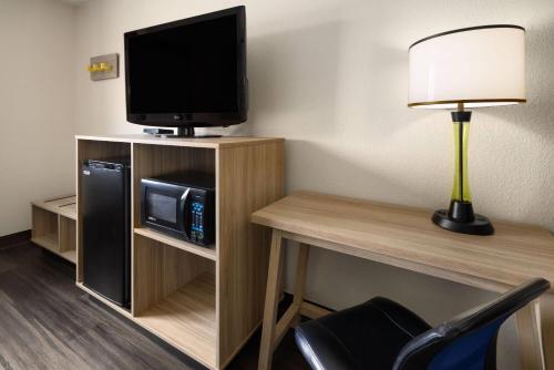a room with a tv and a desk with a microwave at Super 8 by Wyndham South Boston VA in South Boston