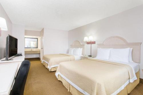a hotel room with two beds and a flat screen tv at Days Inn & Suites by Wyndham Navarre - near Beaches Hurlburt in Navarre