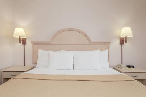 a bedroom with a bed with white pillows and two lamps at Days Inn & Suites by Wyndham Navarre - near Beaches Hurlburt in Navarre