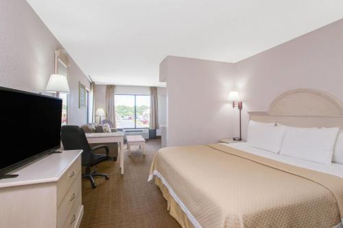 a hotel room with a bed and a desk at Days Inn & Suites by Wyndham Navarre - near Beaches Hurlburt in Navarre
