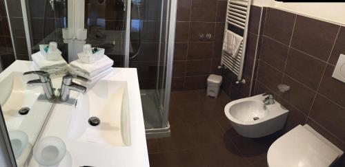 a bathroom with a sink and a shower and a toilet at Hotel Trieste in Morbegno