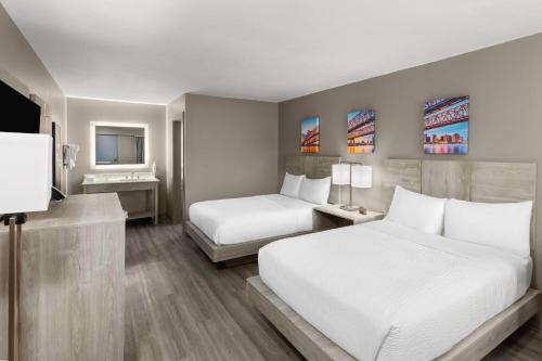 a hotel room with two beds and a television at Days Inn by Wyndham Kenner/New Orleans Airport South in Kenner