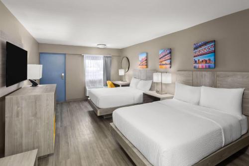 a hotel room with a bed and a television at Days Inn by Wyndham Kenner/New Orleans Airport South in Kenner