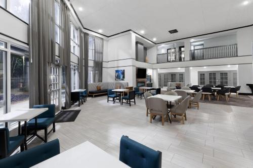 a dining room with tables and chairs and windows at La Quinta Inn & Suites by Wyndham Houston Bush IAH South in Houston