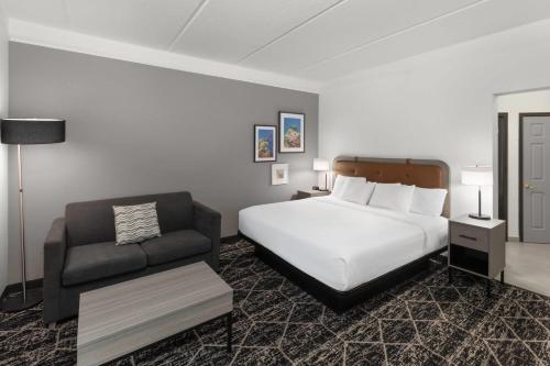 a hotel room with a bed and a couch at La Quinta Inn & Suites by Wyndham Houston Bush IAH South in Houston