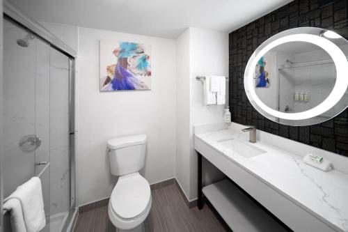 a bathroom with a toilet and a sink and a mirror at La Quinta Inn & Suites by Wyndham Houston Bush IAH South in Houston