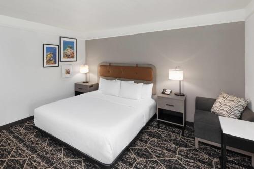 a hotel room with a bed and a chair at La Quinta Inn & Suites by Wyndham Houston Bush IAH South in Houston