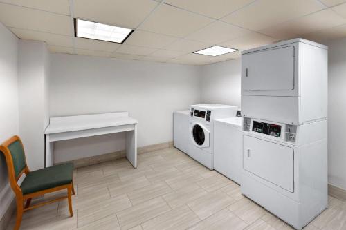 a laundry room with a washer and dryer and a chair at La Quinta Inn & Suites by Wyndham Houston Bush IAH South in Houston