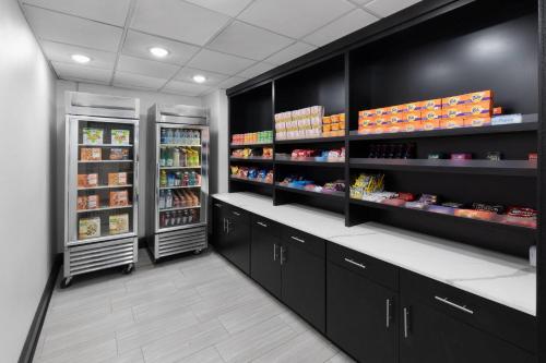 a store aisle with two refrigerators and shelves of food at La Quinta Inn & Suites by Wyndham Houston Bush IAH South in Houston