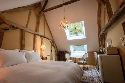 a bedroom with a large bed and a chandelier at Les charpentes des communs du Château du Sollier - Charme Calme Confort Climatisation à 5mn du péage in Bourges