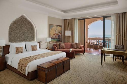 a hotel room with a large bed and a balcony at Marsa Malaz Kempinski, The Pearl in Doha