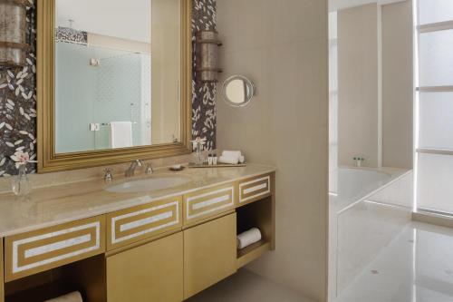 a bathroom with a sink and a mirror and a tub at Marsa Malaz Kempinski, The Pearl in Doha