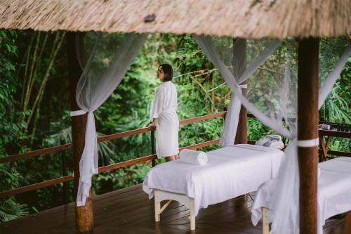 a man standing on a deck with two beds at Alila Ubud in Ubud