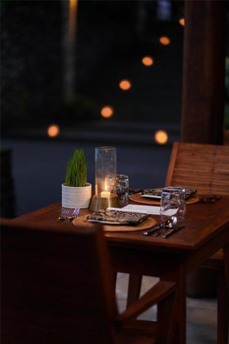 a wooden table with a candle and a plant on it at Alila Ubud in Ubud