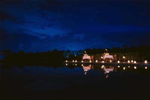a night view of a house with lights on the water at Alila Ubud in Ubud