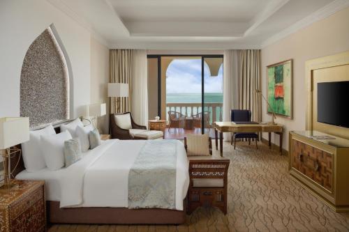 a bedroom with a large white bed and a living room at Marsa Malaz Kempinski, The Pearl in Doha