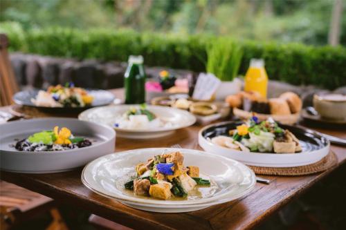a wooden table with plates of food on it at Alila Ubud in Ubud