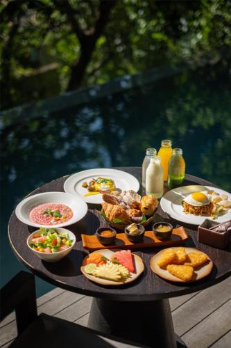 a table filled with plates of food on a table at Alila Ubud in Ubud