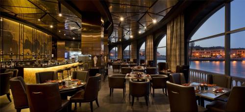 a restaurant with tables and chairs and a view of the water at Marsa Malaz Kempinski, The Pearl in Doha