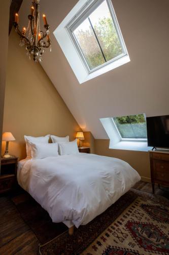 a bedroom with a white bed and two windows at Les charpentes des communs du Château du Sollier - Charme Calme Confort Climatisation à 5mn du péage in Bourges