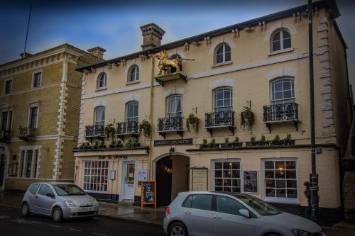 a building with two cars parked in front of it at The Golden Lion Hotel, St Ives, Cambridgeshire - The Coaching Inn Group in St Ives
