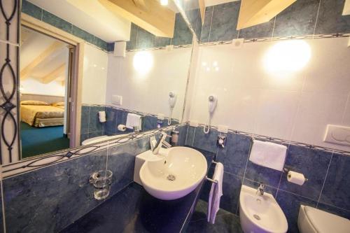 a bathroom with a sink and a toilet and a mirror at Family Hotel Andes - Only for Family in Vigo di Fassa