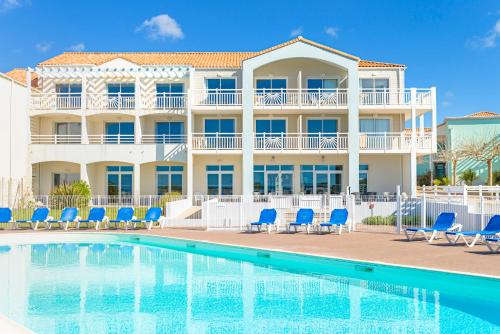 a resort with a swimming pool and blue chairs at Lagrange Vacances L’Estran in Les Sables-dʼOlonne