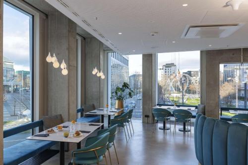 a restaurant with tables and chairs and large windows at nhow Frankfurt in Frankfurt/Main