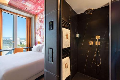 a hotel room with a bed and a shower at nhow Frankfurt in Frankfurt/Main