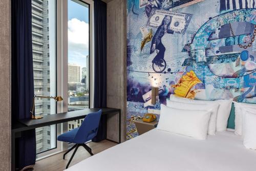 a bedroom with a bed and a desk and a window at nhow Frankfurt in Frankfurt/Main